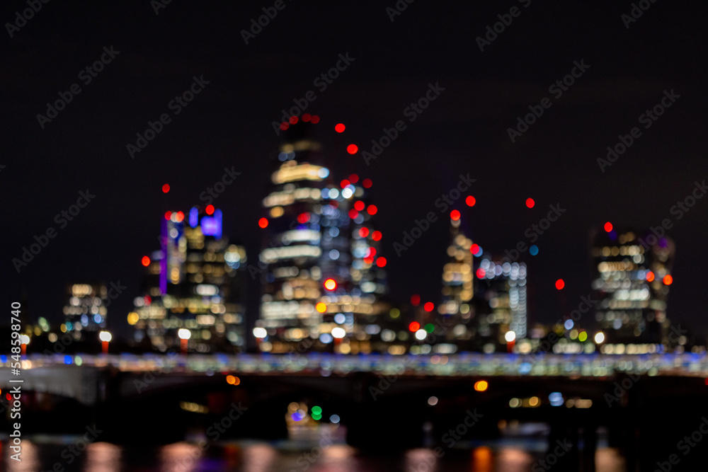 Fototapeta premium Blurred image of Nightlife in London, busy traffic on the bridge over the river Thames near the business district with glittering skyscrapers