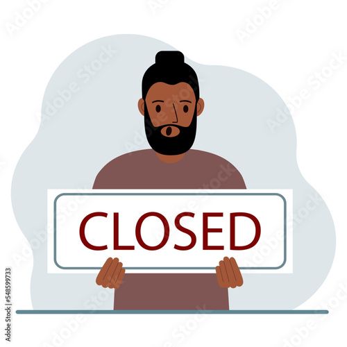 A man holds a sign with the text Closed in his hands.