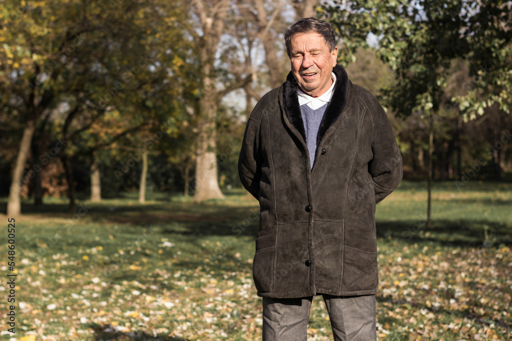 A smiling and satisfied elderly man walking through the park