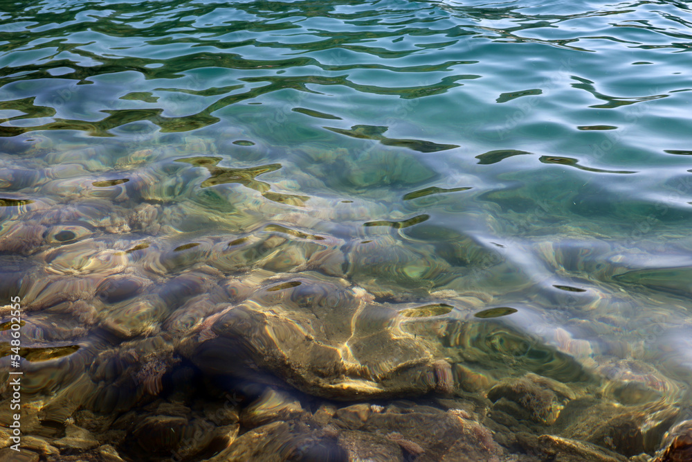 Transparent sea surface with stones on a bottom. Shallow water for background
