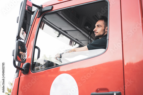 A firefighter driving a truck. The driver looks in the mirror to park.