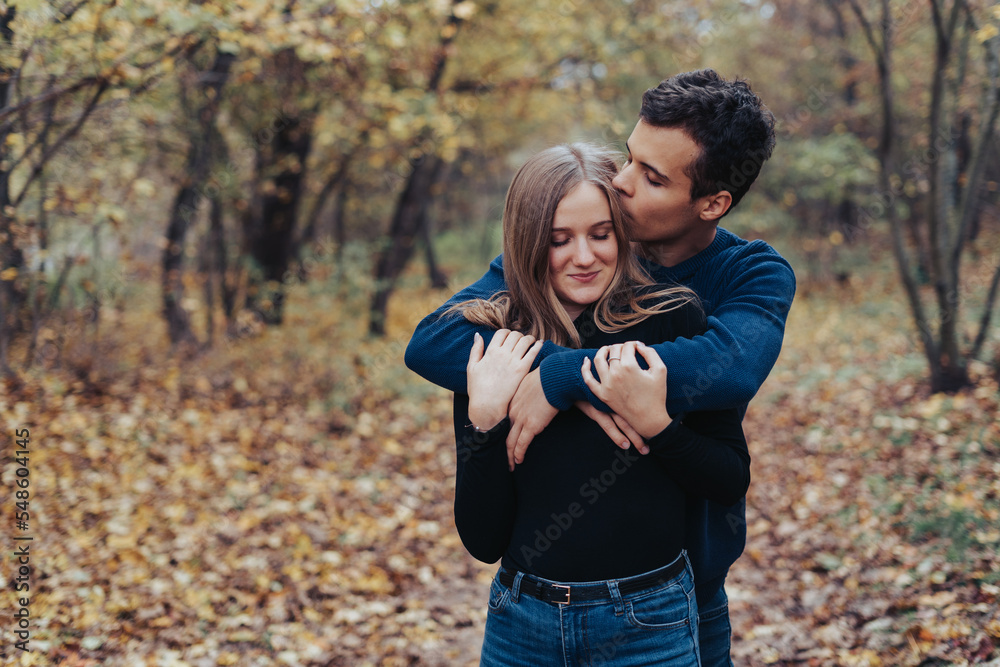 Young cheerful couple in a park, boyfriend gives a kiss to girlfriend Young cheerful couple in a park, boyfriend gives a kiss to girlfriend