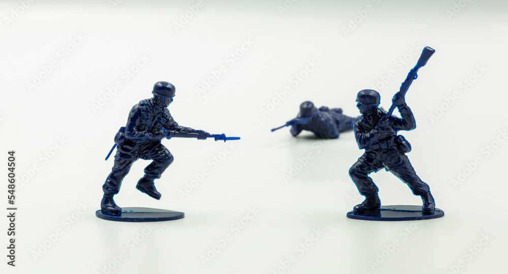 Obraz premium Close-up battle between two military toy soldiers against the white surface. Fighting soldier figure, plastic toys. two toy soldiers fighting against each other on a white background.