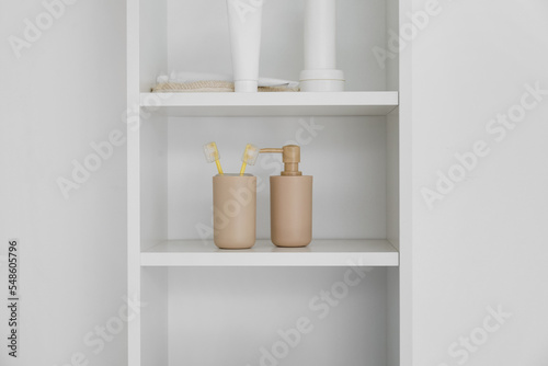 Bath accessories on shelf unit near white wall, closeup