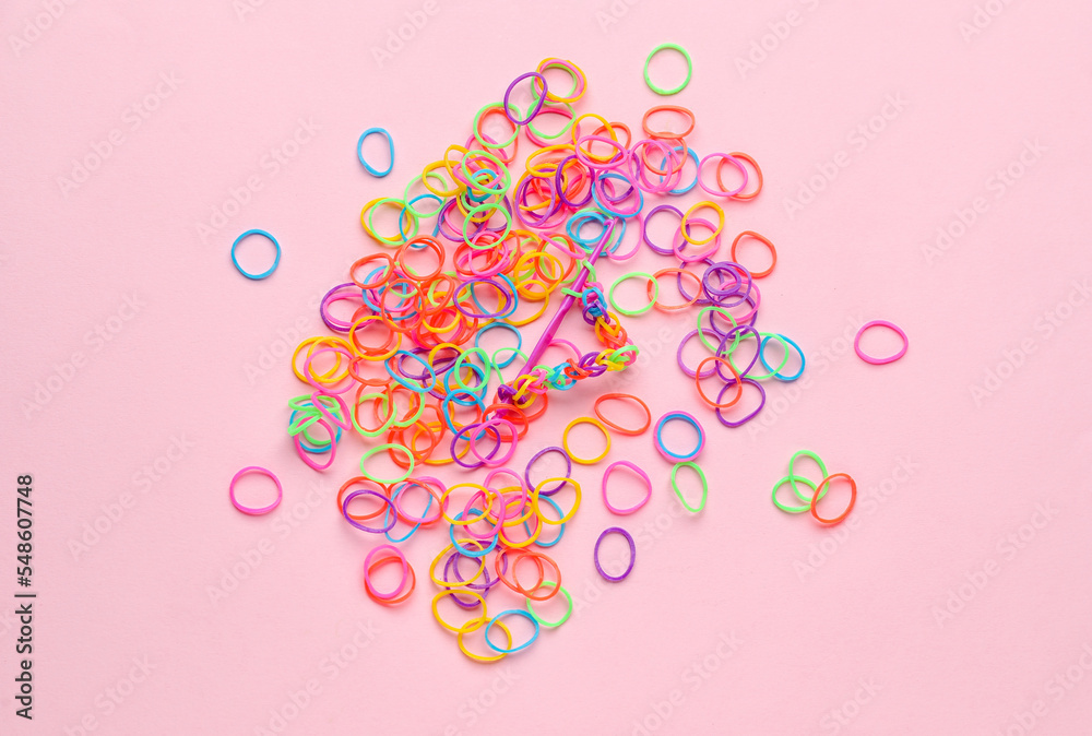 Colorful rubber bands and hook on pink background