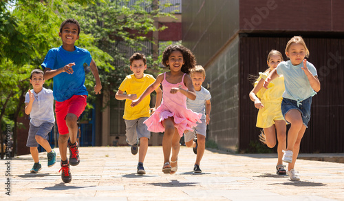 Cheerful active children are racing along the city street