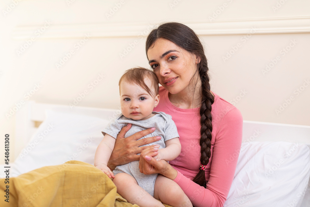 Love and tenderness, motherhood concept. Loving mother caressing her cute baby daughter, lying together on bed