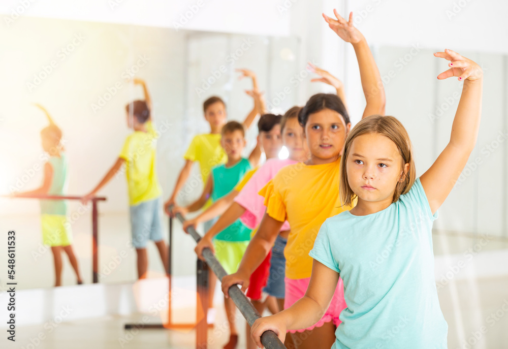 Preteen girls working near ballet barre during group class