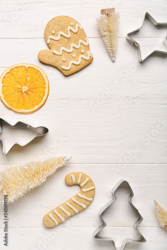 Composition with Christmas decorations, cookies and cutters on light wooden background, closeup