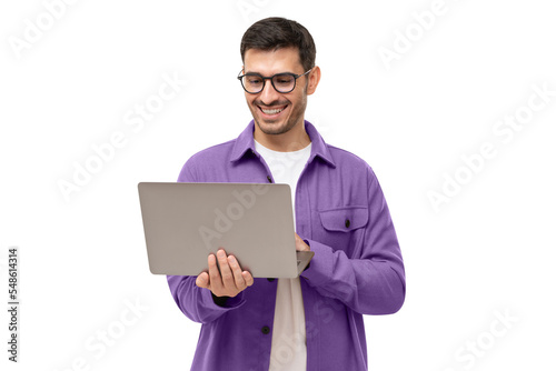 Young happy man standing with opened laptop, browsing online or typing message