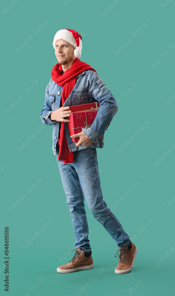 Handsome man in Santa hat with Christmas presents on green background Handsome man in Santa hat with Christmas presents on green background
