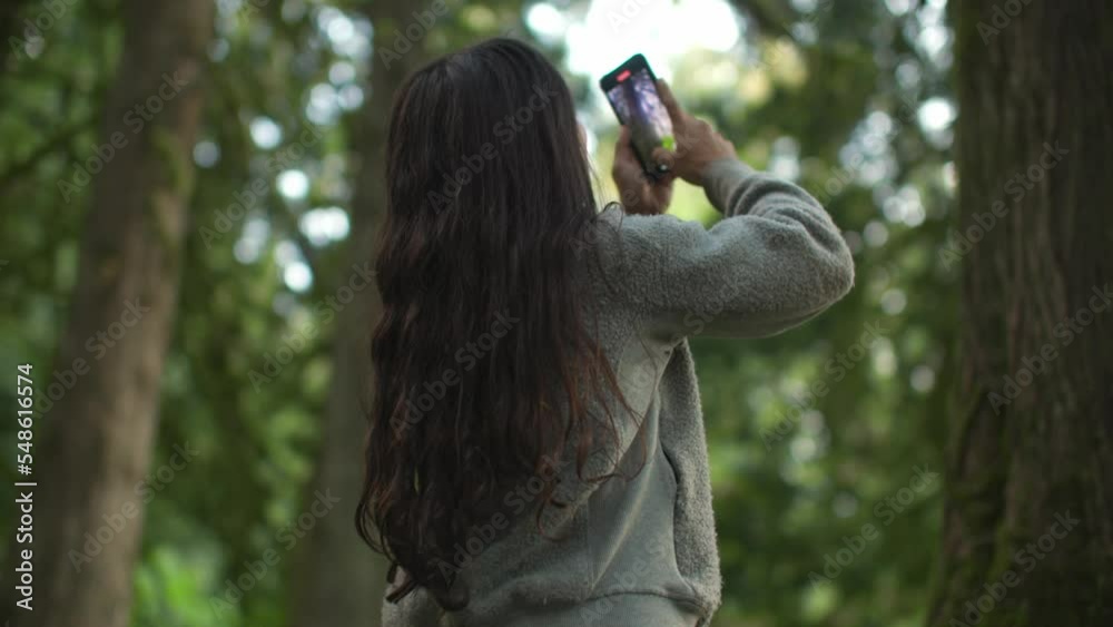 Female content creator taking video for social media in beautiful forest, phone