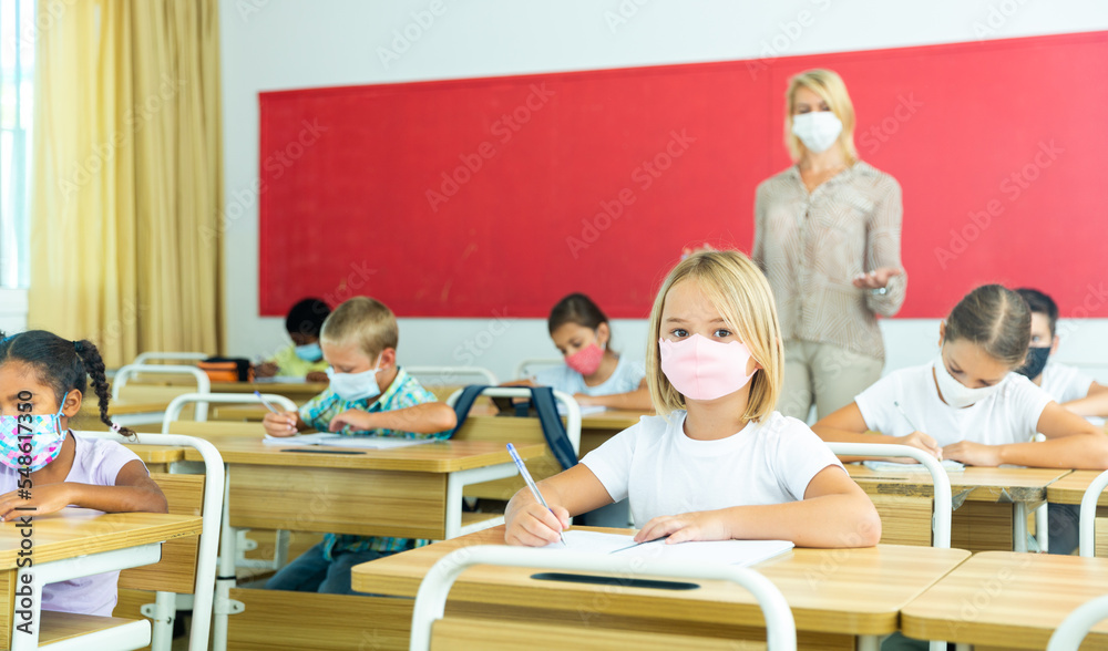 © JackF - Diligent tween girl in protective mask studying in school with classmates. New life reality in coronavirus pandemic © JackF - Diligent tween girl in protective mask studying in school with classmates. New life reality in coronavirus pandemic