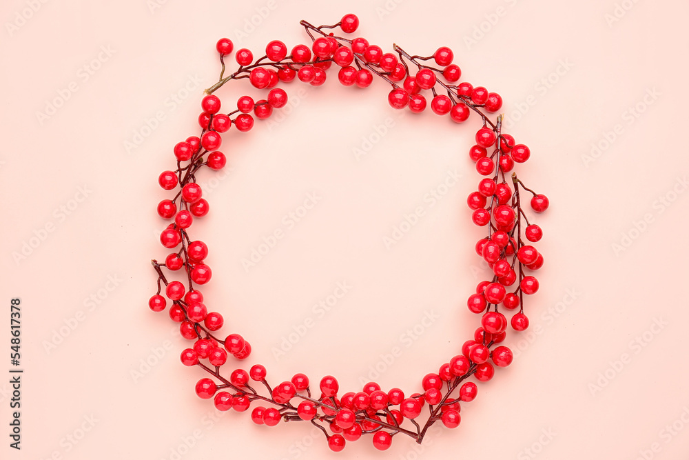 Frame made of branches with red berries on color background