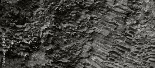 Dark gray basalt rock wall background. Horizontal textured banner. 