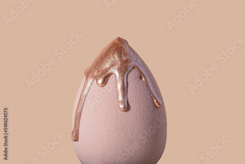 Closeup photography of beauty blender with dripping bronzer on it.Neutral beige background,large banner with copy space.