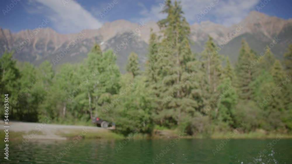 Carefree man dives off dock into lake, mountain backdrop Carefree man dives off dock into lake, mountain backdrop