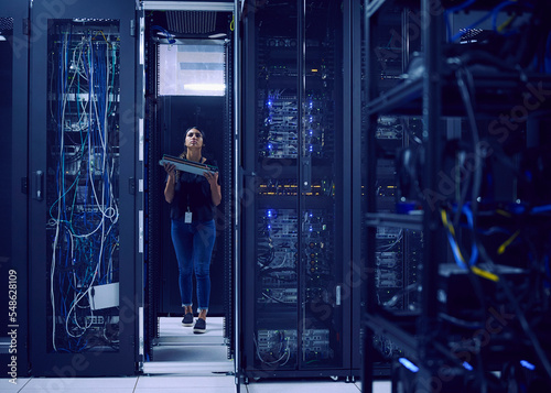 Female technician carrying hard drive in server room photo