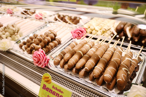 Chocolate fondue with fresh banana. Fondue with melted chocolate and Banana. Banana skewers with melted chocolate on sticks at fruit stall for sale at German Christmas market festival