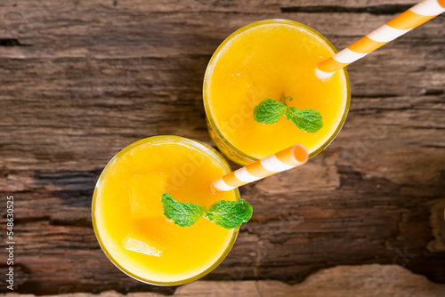 Mango smoothies orange colorful fruit juice beverage healthy high protein the taste yummy in glass on wood background from top view.
