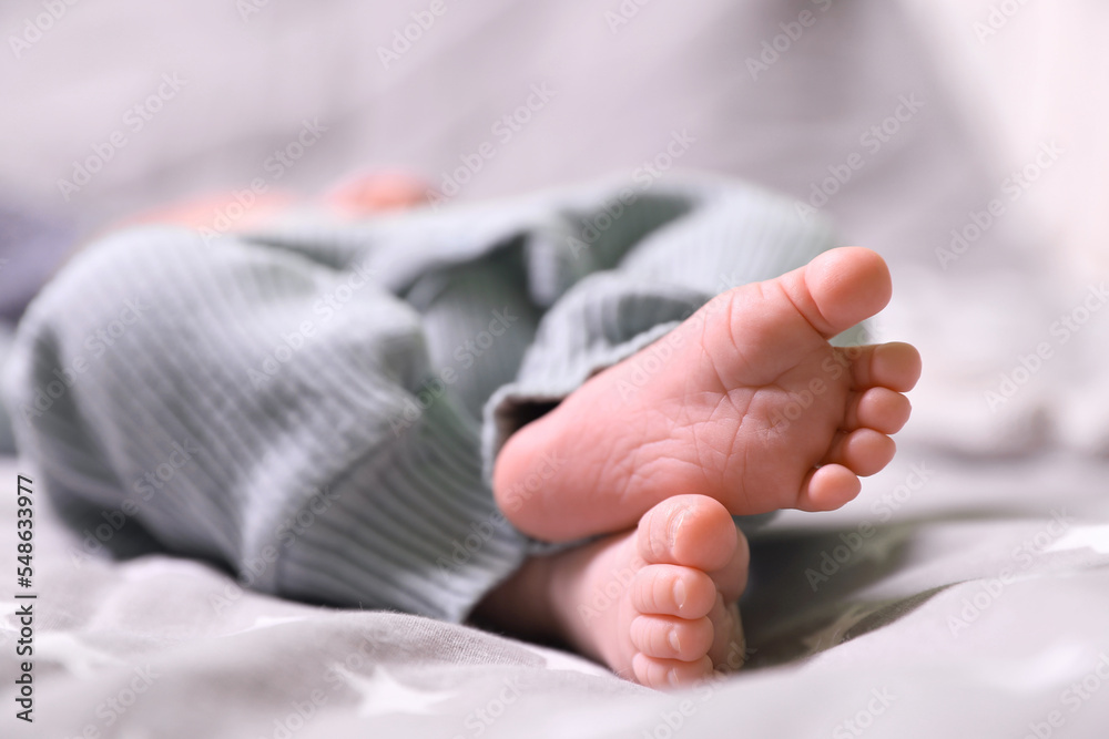 Cute newborn baby lying on bed, closeup of legs Cute newborn baby lying on bed, closeup of legs