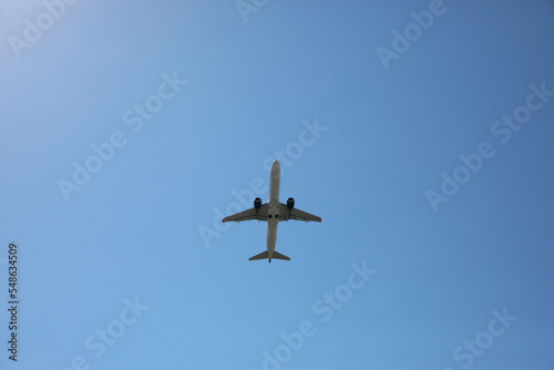 Modern white airplane flying in sky, bottom view