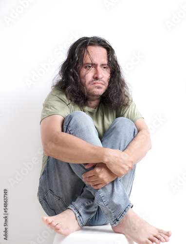Fotografija a disheveled man with a blank stare huddled and anguished