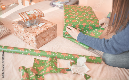 Young woman's hands wrap christmas presents with decorative paper for her family during the christmas holidays.