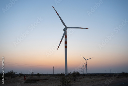 Pre dawn light in desert sky with Electrical power generating wind mills producing alterative eco friendly green energy for consumption by local people. Thar desert, Rajasthan, India.