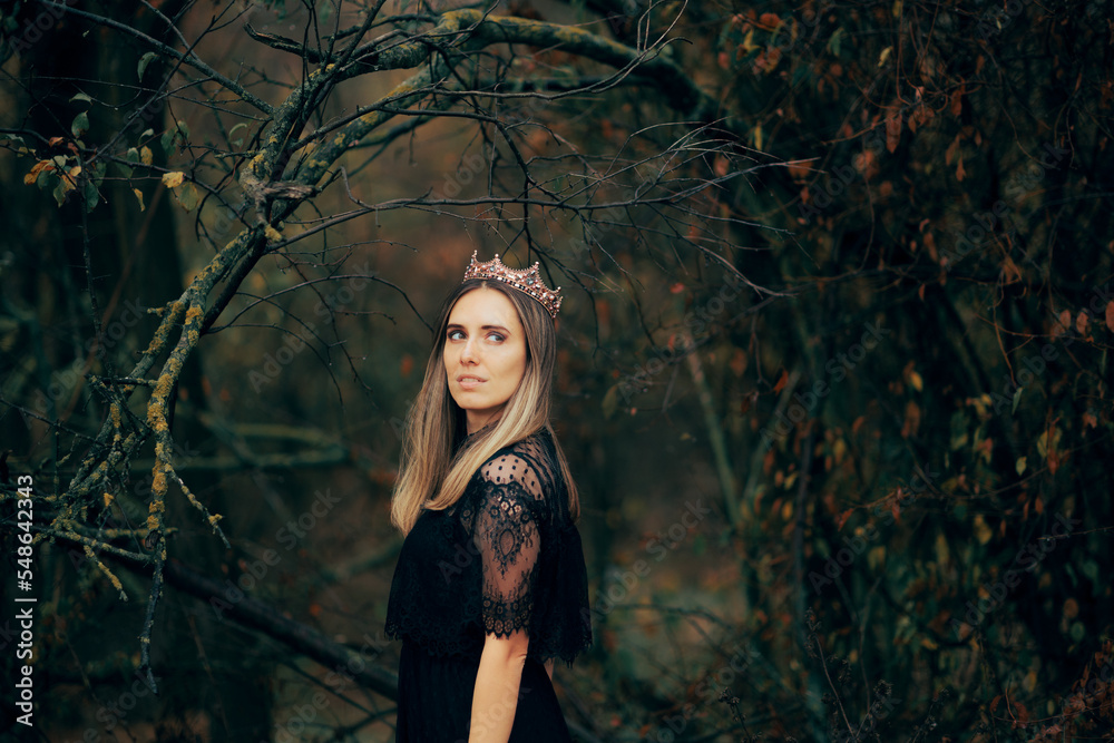 Fototapeta premium Beautiful Queen Wearing a Crown and a Black Lace Dress. Gorgeous dark princess standing alone in the forest 