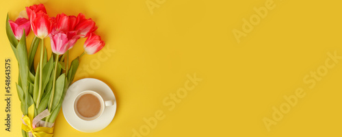 Beautiful spring breakfast on Mothers or Womans International day 8 march, 14 february. Bouquet of pink tulips, coffee cup on bright yellow table. Flat lay, banner for site, seasonal flyer