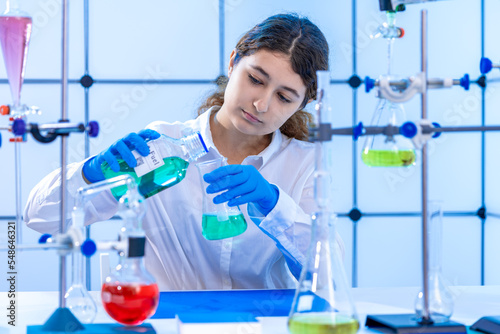 Fototapeta Naklejka Na Ścianę i Meble -  young adult female scientist conducts a chemical experiment in a hydrocarbon synthesis laboratory