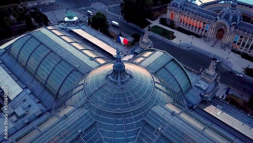Top down aerial shot of historic site The Grand Palais des Champs-Elysees of Paris, a large exhibition hall and museum complex with glass roof top in morning, featuring french flag on the dome . photo