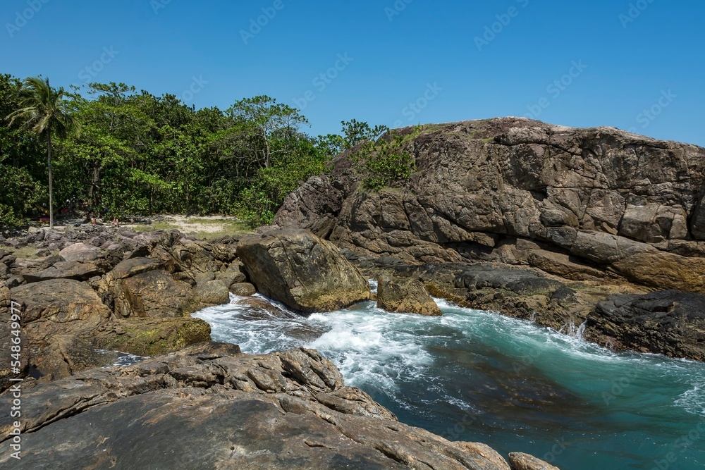 Natural landscape in the Escape of Islands, Barra do Sahy, São Sebastião, Brazil. As Ilhas. Turquoise sea and waves hitting the rocks.