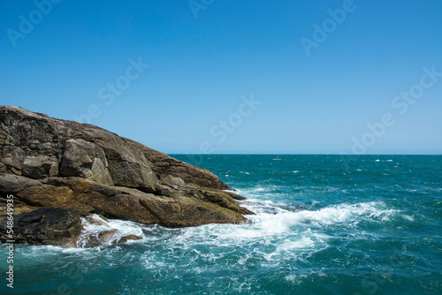 Natural landscape in the Escape of Islands, Barra do Sahy, São Sebastião, Brazil. As Ilhas. Turquoise sea and waves hitting the rocks.