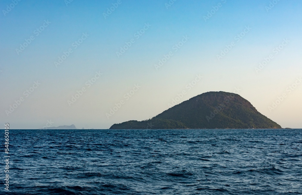 Wheat heap island at sunset. Ilha do Montão de Trigo. Environmental reserve in the sea of São Sebastião, Brazil. In the background, the Alcatrazes archipelago.