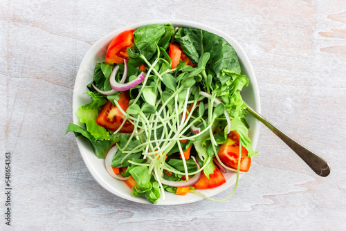 SunflowerHealthy food sunflower sprout salad has leave lettuce vegetable tomato in bowl on white wood background.