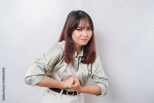 Excited Asian woman wearing a sage green shirt showing strong gesture by lifting her arms and muscles smiling proudly