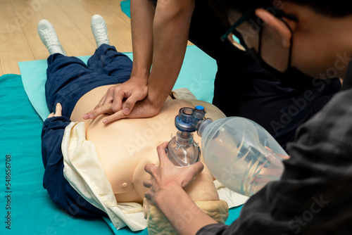 Demonstrating CPR (Cardiopulmonary resuscitation) training medical procedure on CPR doll in the class.Paramedic demonstrate first aid practice for save life.Doctor holding breathing bag(Ambu bag). photo