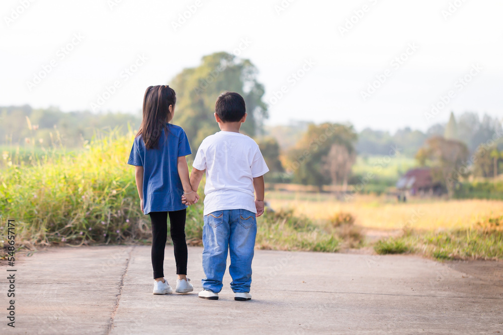 Happy children playing outdoors in park. Asian kids playing in garden, boy and girl holding hands Happy children playing outdoors in park. Asian kids playing in garden, boy and girl holding hands