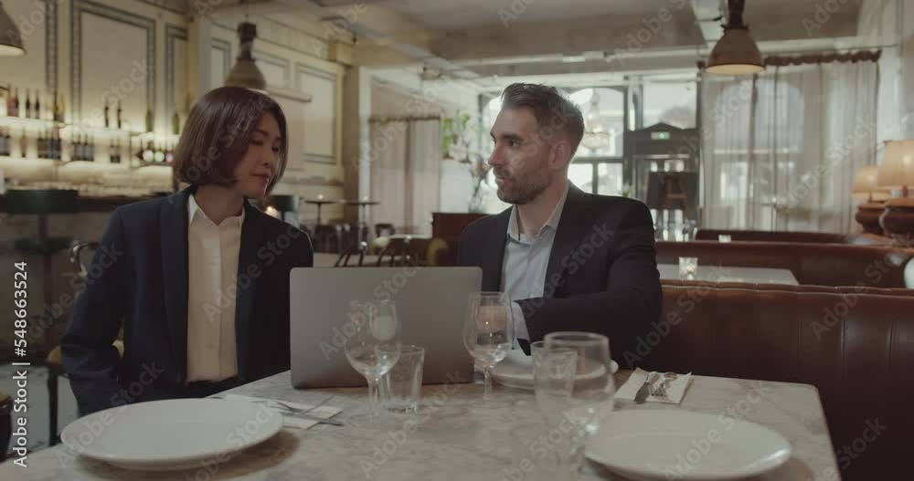 Businesspeople using Laptop and having a Meeting in a Restaurant Businesspeople using Laptop and having a Meeting in a Restaurant
