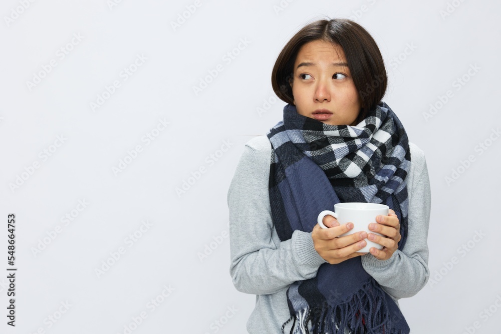 Asian woman cold flu holding a mug of tea smile in plaid with fever sick of the virus on a white background, copy space Asian woman cold flu holding a mug of tea smile in plaid with fever sick of the virus on a white background, copy space