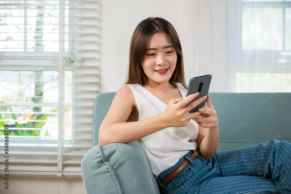 Happy beautiful woman relaxation she shopping online with smartphone, Smiling Asian female sitting on sofa talking mobile smart phone at living room at home, Social media networks communication Happy beautiful woman relaxation she shopping online with smartphone, Smiling Asian female sitting on sofa talking mobile smart phone at living room at home, Social media networks communication