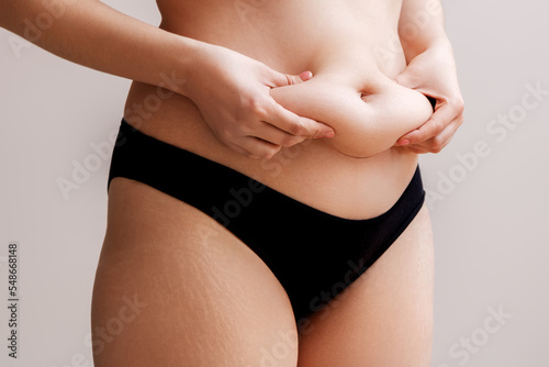 Fat woman hand holding excessive belly fat . Healthcare and woman diet lifestyle concept to reduce belly and shape up healthy stomach muscle .  photo