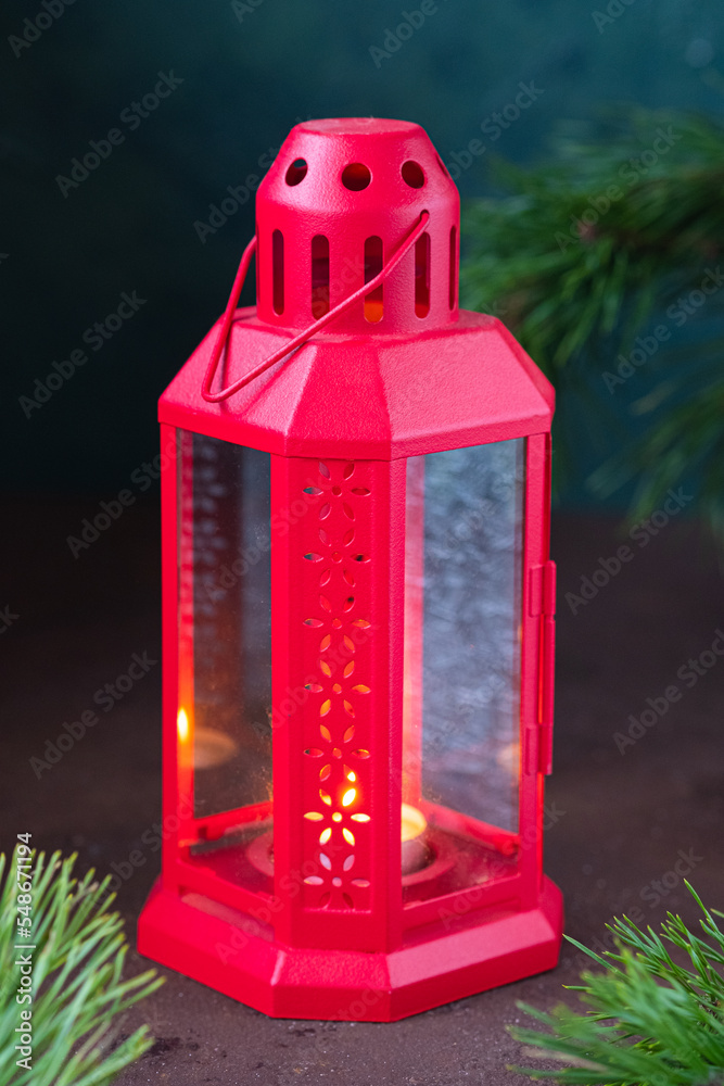 Festive composition, red metal lantern with a candle and fir branches on a brown concrete background. Merry Christmas concept. Festive composition, red metal lantern with a candle and fir branches on a brown concrete background. Merry Christmas concept.