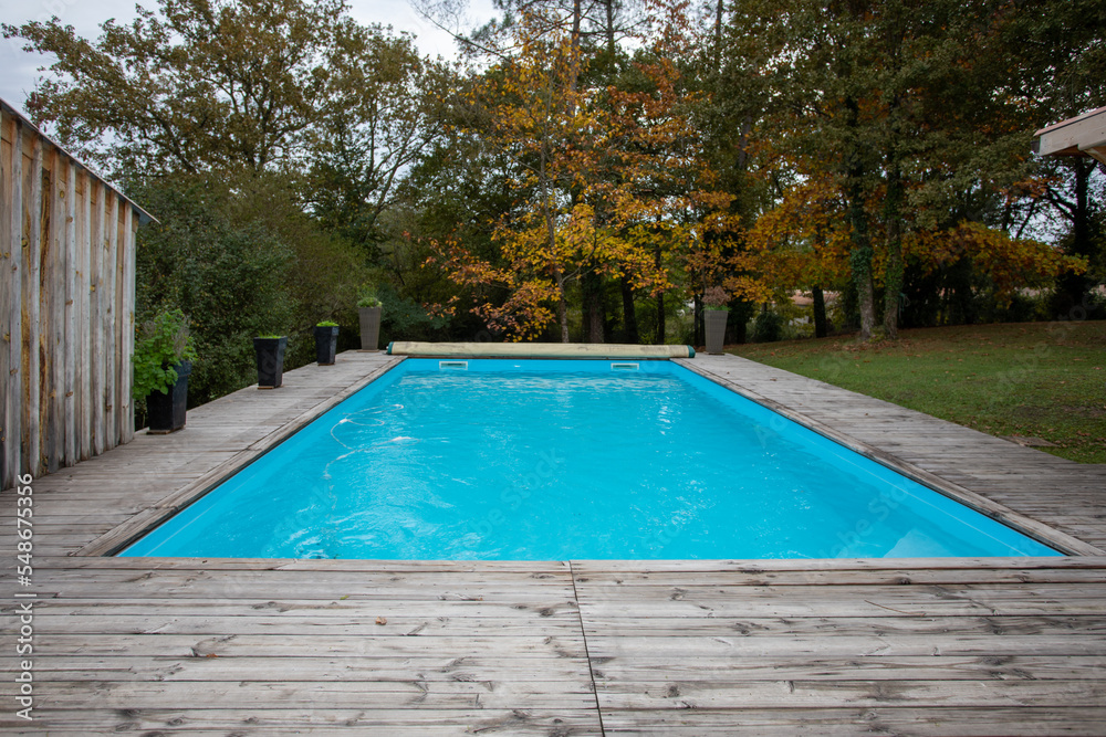 home blue swimming pool with wooden terrace garden house
