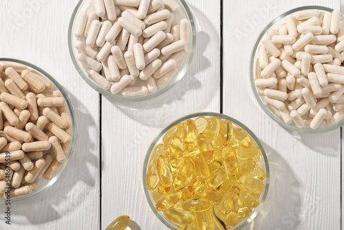 various supplement pills omega 3 and vitamins in petri dishes. healthcare support, top view, flat lay.