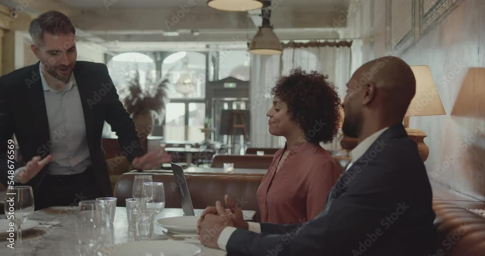 Three Businesspeople having a Meeting in a Restaurant using Laptop Three Businesspeople having a Meeting in a Restaurant using Laptop