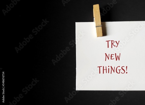 Note stick on copy space background with text written TRY NEW THINGS , concept of discover new interests and hobbies, get out of your comfort zone and try new things