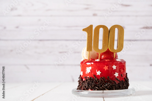 The number Hundred on a red birthday cake on a light background